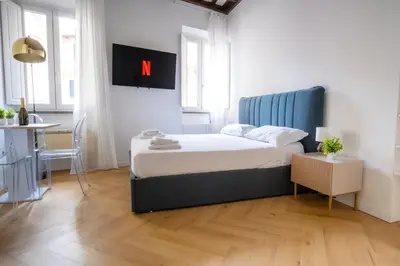 a bedroom with a bed with a blue headboard and a table at Elegantis Trevi Suite Apartment - Just 50m from Trevi Fountain in Rome