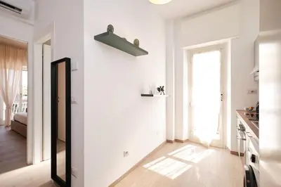 a living room with a white wall and a mirror at Ospedale Gemelli-Vaticano Domus Di Pace 1BDR by Hôtea in Rome