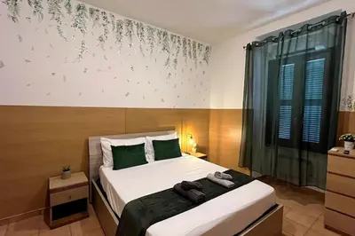 a bedroom with a bed with green and white sheets at Dreams Under the Trees - Metro Roma Termini in Rome