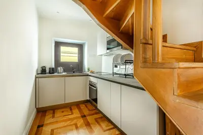 a kitchen with white cabinets and a wooden floor at iFlat Campo dei Fiori View and SPA in Rome