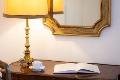 a table with a lamp and a book and a cup of coffee at Amazing Domus Ruspoli in Rome