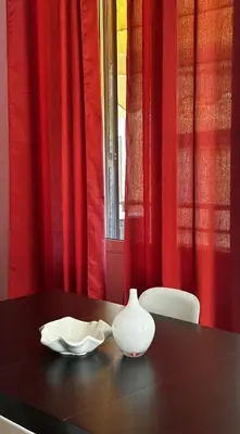 a black table with a white vase on a table with red curtains at ColleVaticano Roma in Rome