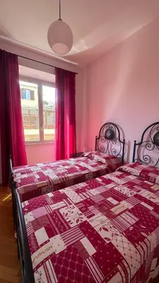 two beds in a bedroom with red curtains at ColleVaticano Roma in Rome