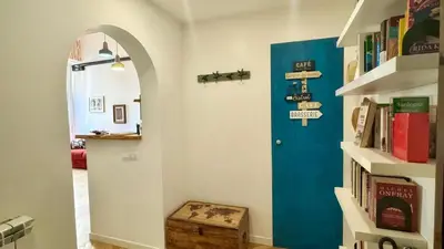 a hallway with a blue door and a shelf with books at Rome Like Home in Rome