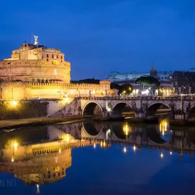 a building with a bridge over a river at night at King's Place in Rome