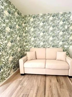 a white couch in a living room with floral wallpaper at Green House Rome in Rome