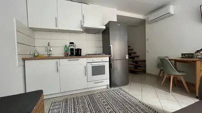 a kitchen with white cabinets and a table and a refrigerator at Testaccio Terrace,Perfect for families or small groups in Rome