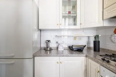 a kitchen with white cabinets and a white refrigerator at Piazza Caprera - Family Apartment in Rome
