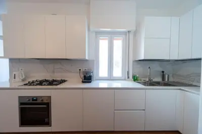 a white kitchen with white cabinets and a window at Cardinal Mistrangelo - next to the metro station, large and comfortable penthouse with terrace in Rome