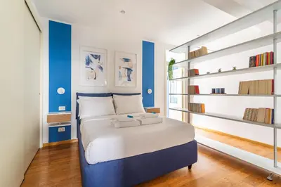 a bedroom with a bed with blue walls and shelves at iFlat Discovering Monti - Charming and Modern apt in Rome