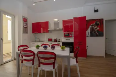 a kitchen with red cabinets and a white table and chairs at rainbow al colosseo in Rome