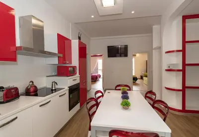 a kitchen with red cabinets and a white table and chairs at rainbow al colosseo in Rome