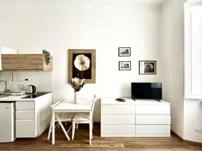 a kitchen with white cabinets and a table and a tv at Camilla Charme in Rome