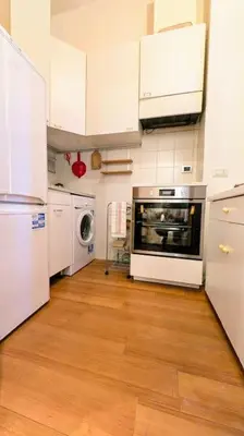 a kitchen with white appliances and a wooden floor at Cozy Home in San Cosimato in Rome