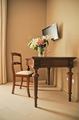 a vase of flowers on a table with a chair at B&B Carini 58 in Rome
