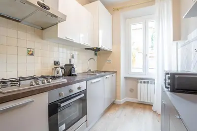 a kitchen with white cabinets and a sink and a window at Daplace - Palazzina Cosima in Rome