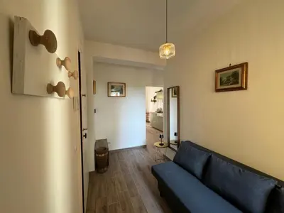 a living room with a blue couch and a hallway at Apt with balcony in Roman Quiet in Rome