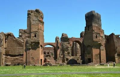 an ancient ruins with people standing in the grass at Atticoromantica in Rome