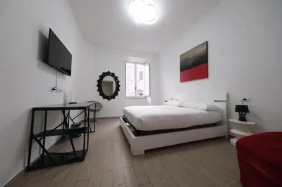 a white bedroom with a bed and a flat screen tv at Roman Forum Holiday Termini in Rome