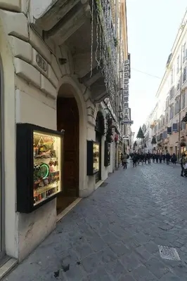 a street with people walking down a street at Gravina Suite Frattina in Rome