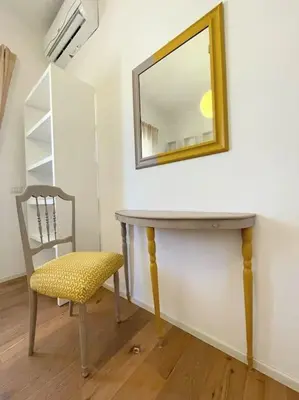 a mirror on a wall next to a table and a chair at MilleStorie House Rome in Rome
