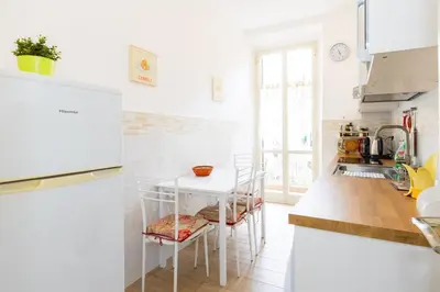 a white kitchen with a table and chairs at Vespasiano 49 in Rome