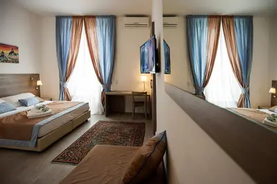 a hotel room with two beds and two windows at Roman Holidays cuore dell'Impero in Rome