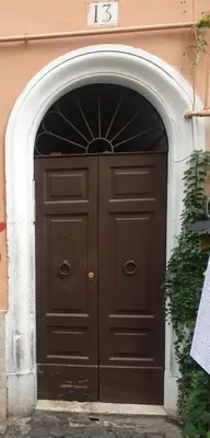 a large wooden door in a building with an arch at San Cosimato cozy flat in Rome