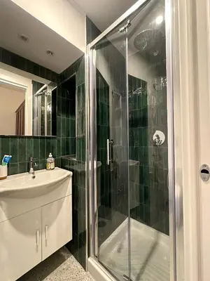 a green tiled bathroom with a shower and a sink at FL Suites - Vatican in Rome