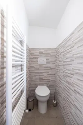 a bathroom with a toilet in a brick wall at Elegant Ostiense Suite in Rome