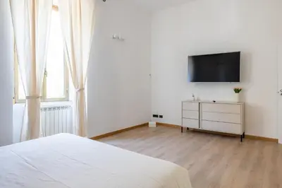 a white bedroom with a bed and a flat screen tv at Elegant Ostiense Suite in Rome