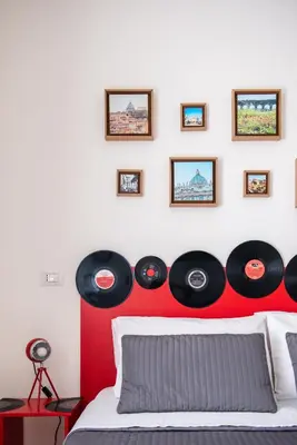 a bedroom with a red headboard with records on the wall at Grammy Suite in Rome