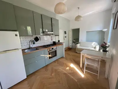 a kitchen with blue cabinets and a table and a white refrigerator at Lotto 21 della Garbatella in Rome