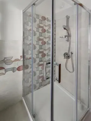 a shower with a glass door with a stone wall at Oasi Ridolfi in Rome