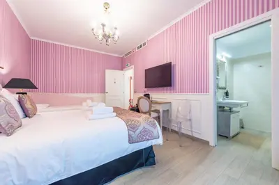 a bedroom with pink walls and a bed and a desk at Catone Vatican Suites by Ghor in Rome