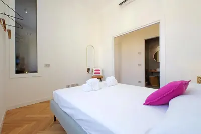 a bedroom with a large white bed with pink pillows at Scipioni in Rome