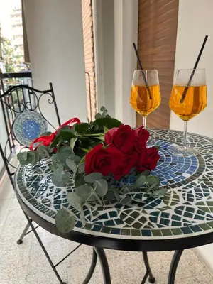 a table with a bouquet of roses and two wine glasses at Dodo House in Rome