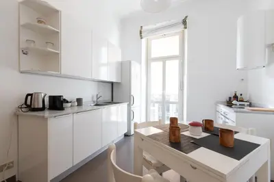 a kitchen with white cabinets and a table with chairs at Suite Bormida - Coppedè in Rome