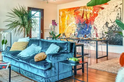 a living room with a blue couch and tables at Skylife Art Gallery Loft - Riverfront Art Sanctuary in Rome