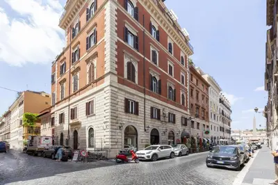 a large brick building with cars parked on a street at Spanish Steps Historic Apartment in Rome