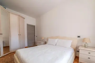 a white bedroom with a bed and a night stand at Giorgia Flat - Tiburtina Train Station - Wi-Fi in Rome