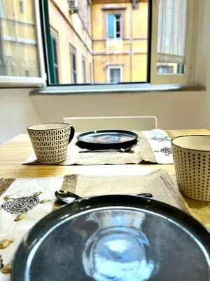 a table with a plate and two bowls on it at Silla Studiò - piccolo appartamento a due passi dal Vaticano in Rome