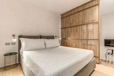 a bedroom with a white bed with a wooden headboard at Domus Romano Piazza Farnese in Rome