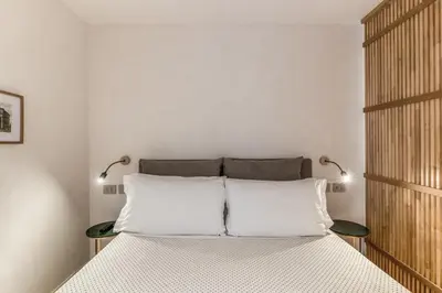 a white bedroom with a bed with two lamps at Domus Romano Piazza Farnese in Rome