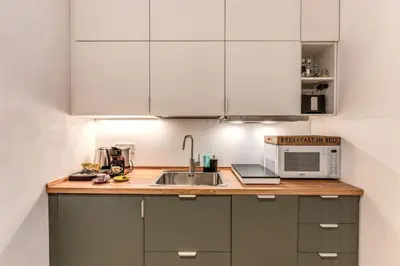 a kitchen with white cabinets and a sink and a microwave at Domus Romano Piazza Farnese in Rome