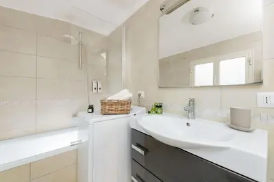 a white bathroom with a sink and a mirror at Big Flat in the Heart of Trastevere 4 bedrooms 3 bath in Rome