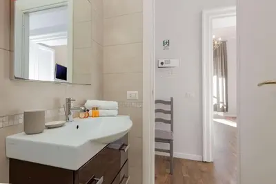 a white bathroom with a sink and a mirror at Big Flat in the Heart of Trastevere 4 bedrooms 3 bath in Rome