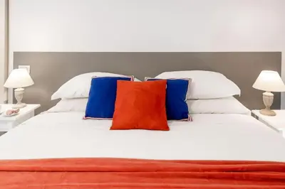 a large white bed with blue and red pillows at Big Flat in the Heart of Trastevere 4 bedrooms 3 bath in Rome
