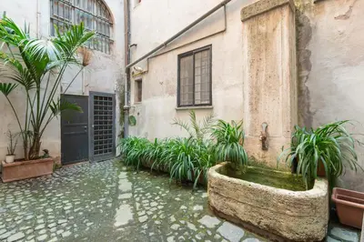 a courtyard with a stone tub with plants in front of a building at Maison Leo a Largo Argentina in Rome
