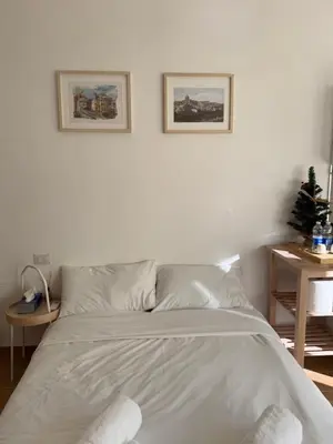 a white bed in a bedroom with two pictures on the wall at Flat 7 Rome Guesthouse in Rome